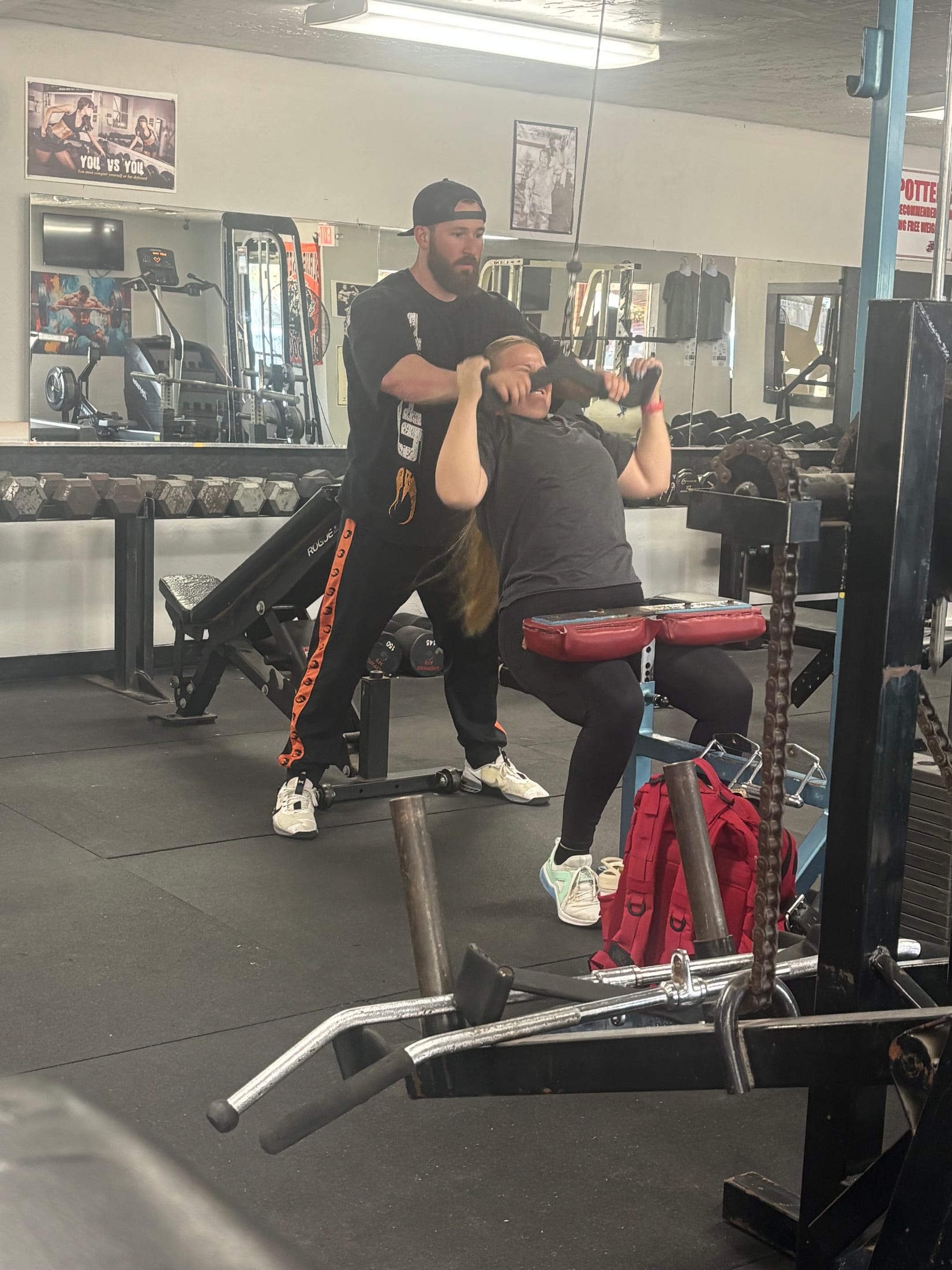 A coach guiding a member through a machine exercise