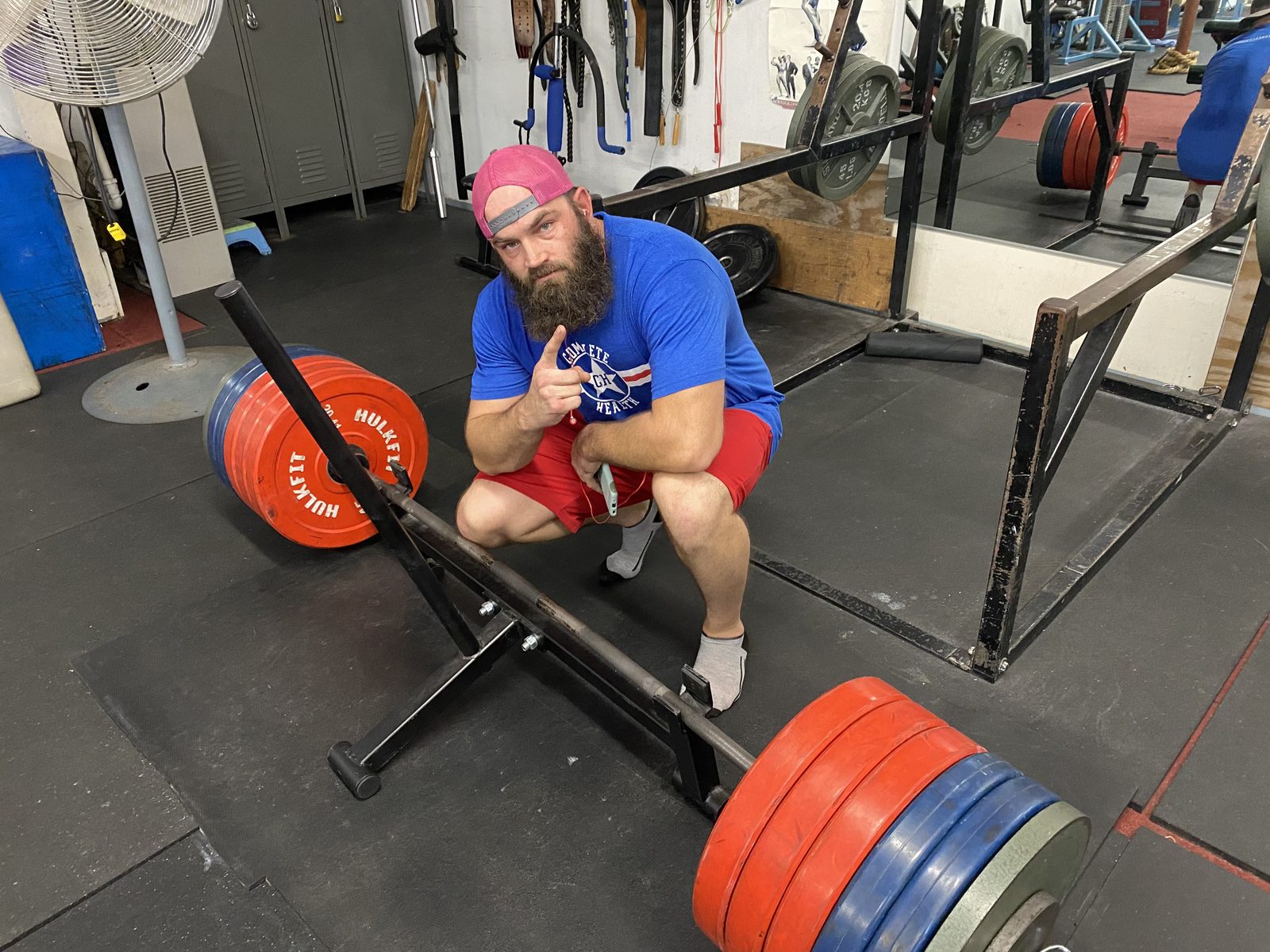 A member crouching beside a heavily loaded deadlift bar