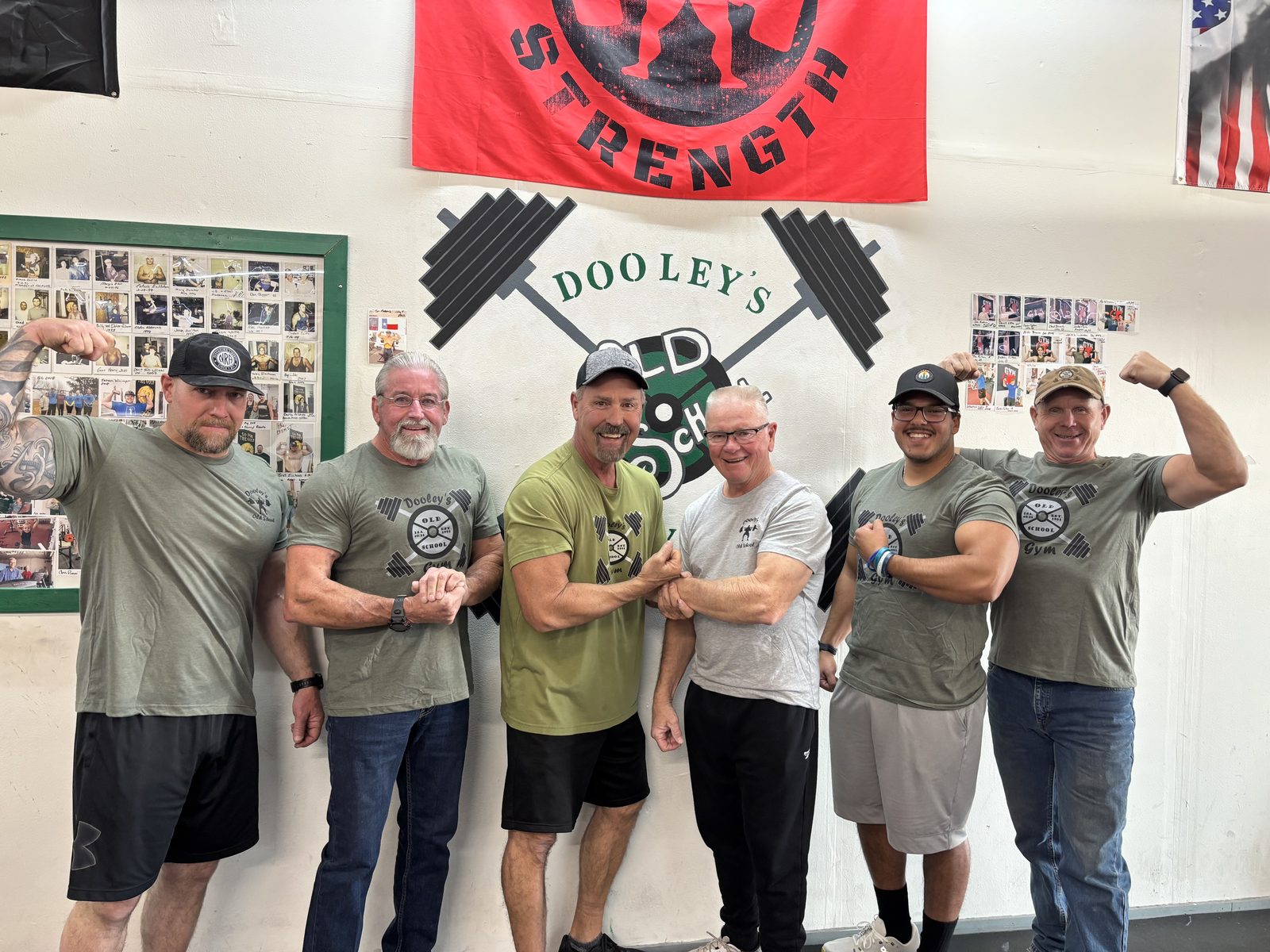 Six Dooley’s members posing together in front of the gym wall